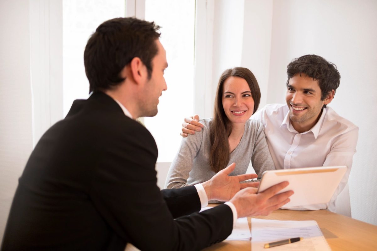 Sunrise Services image featuring a man explaining documentation to a happy couple.